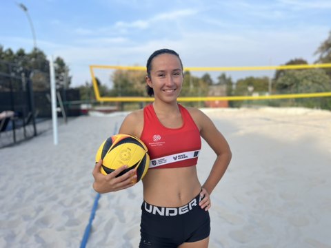 Denisa holding a volleyball on the outdoor court