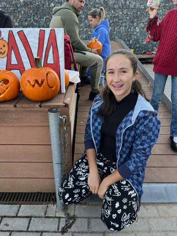 Denisa beside carved pumpkins at a community event