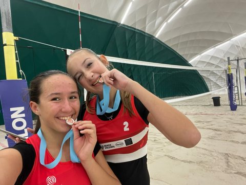Beach volleyball teammates with medals