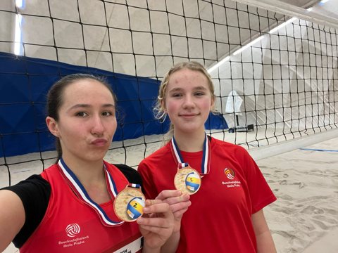 Two volleyball players displaying medals