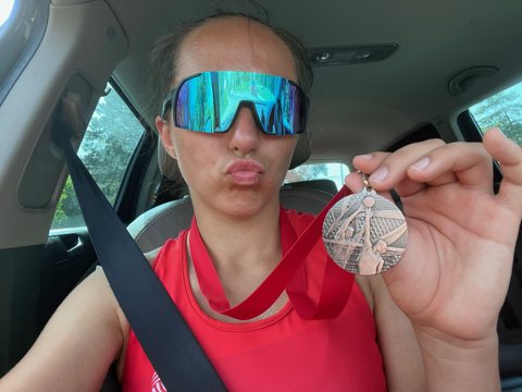Denisa displaying a medal in her red jersey