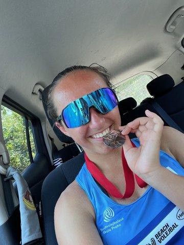 Denisa celebrating with a medal in her blue jersey