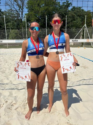 Volleyball teammates displaying medals and certificates outdoors