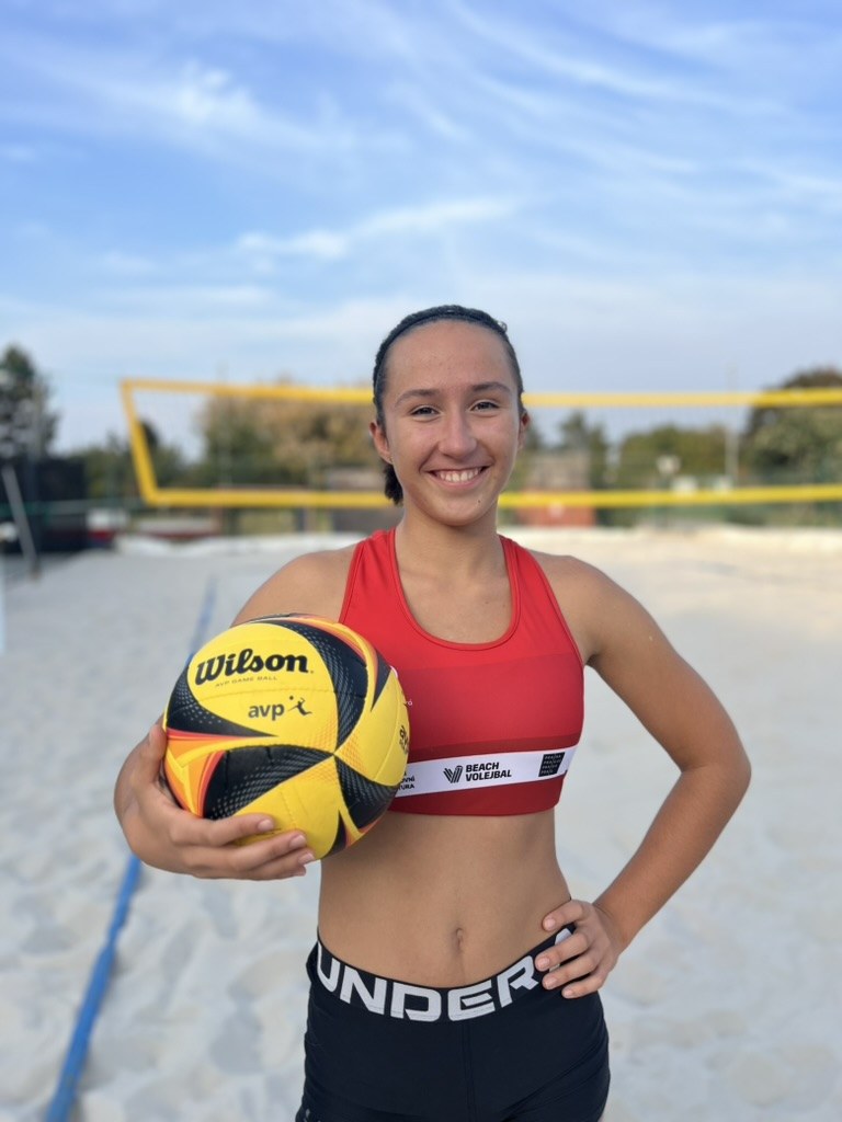 Denisa smiling on a beach volleyball court