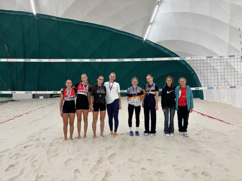 Beach volleyball players at an indoor tournament awards ceremony