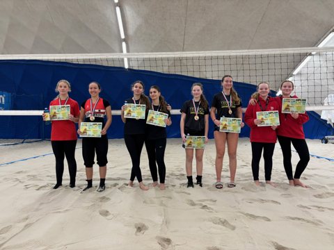 Beach volleyball players at an indoor tournament awards ceremony