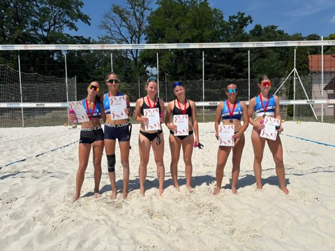 Beach volleyball players at an outdoor tournament awards ceremony